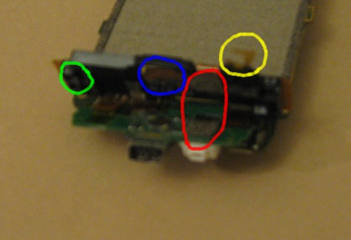 Flip the motherboard such that the trackball is facing upwards and the bottom of the phone is closest. The adhesive tapes are located towards the right of the smaller angled circuit board and the small plastic clip is located to the far left on the underside.